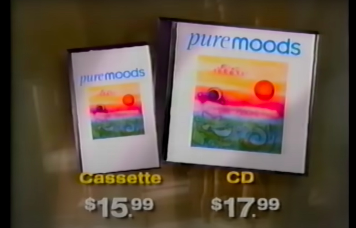 screenshot from a 1997 commercial for the "Pure Moods" compilation album. It shows a cassette tape of the album on the left, and the CD version on the right. Below each are the prices: Cassette $15.99; CD $17.99