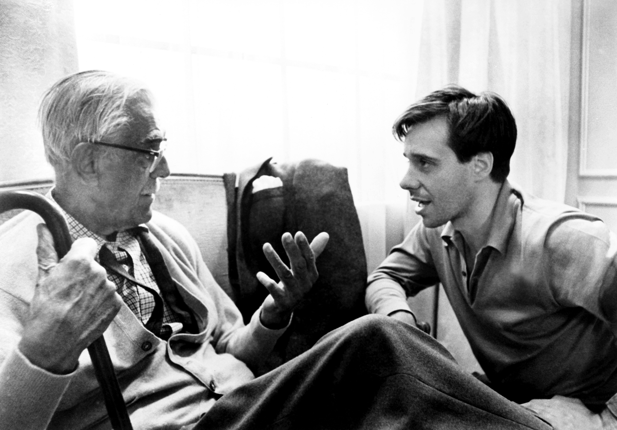 black and white behind-the-scenes image from the 1968 movie "Targets." Star Boris Karloff is seated on the left, looking to his left at director Peter Bogdanovich, also seated, as they discuss a scene.