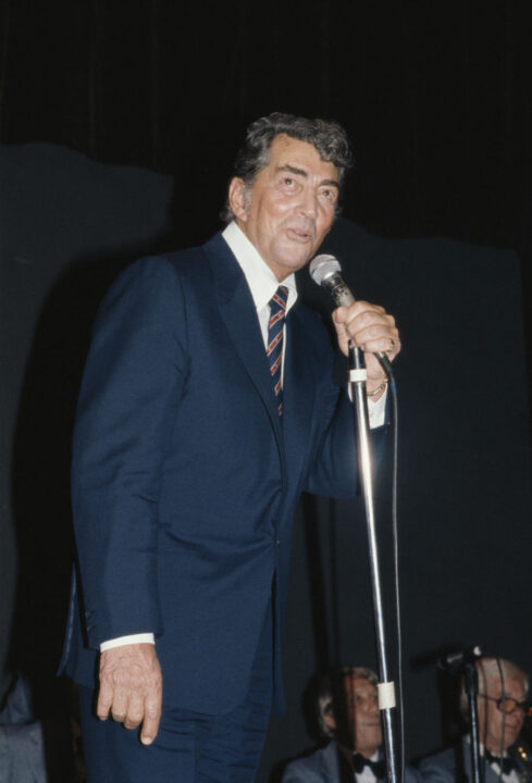 Dean Martin (1917-1995), US singer and actor, singing into a microphone at the Variety Club luncheon, held in his honour, at the Hilton Hotel, in London, England, United Kingdom, 7 May 1983