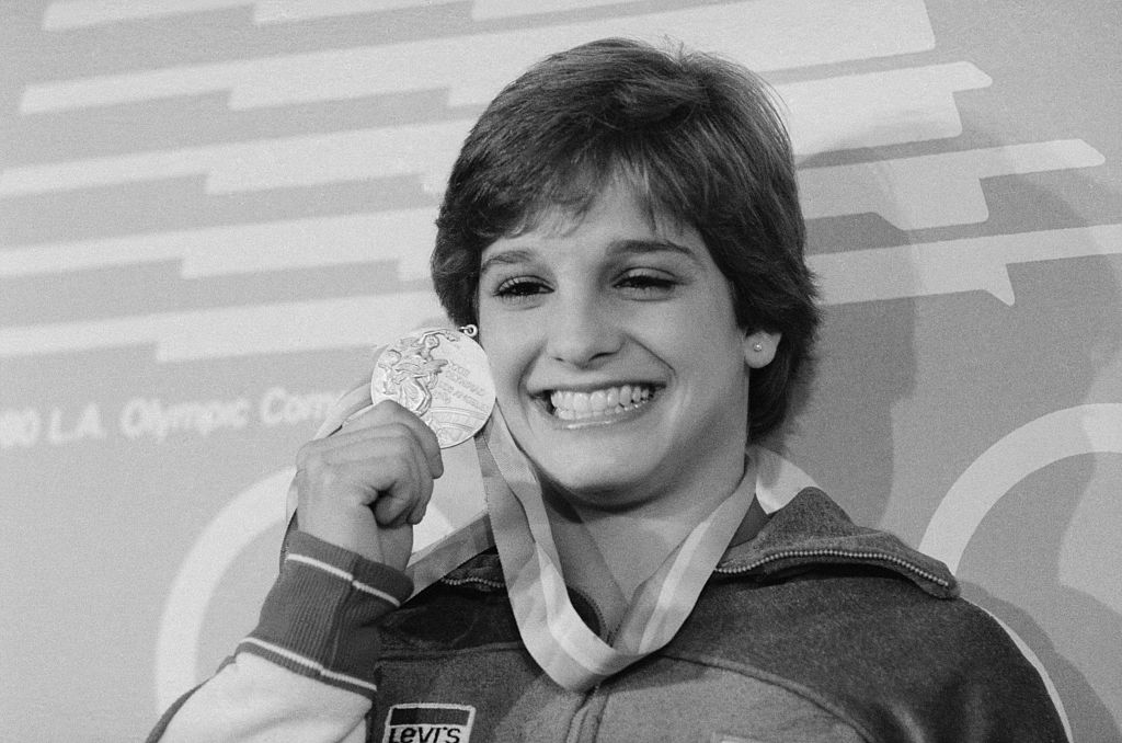 American Olympic gymnast Mary Lou Retton holds up her gold medal at a press conference during the 1984 Summer Games in Los Angeles. Mary Lou, who has also won a silver, has a chance at four more medals.