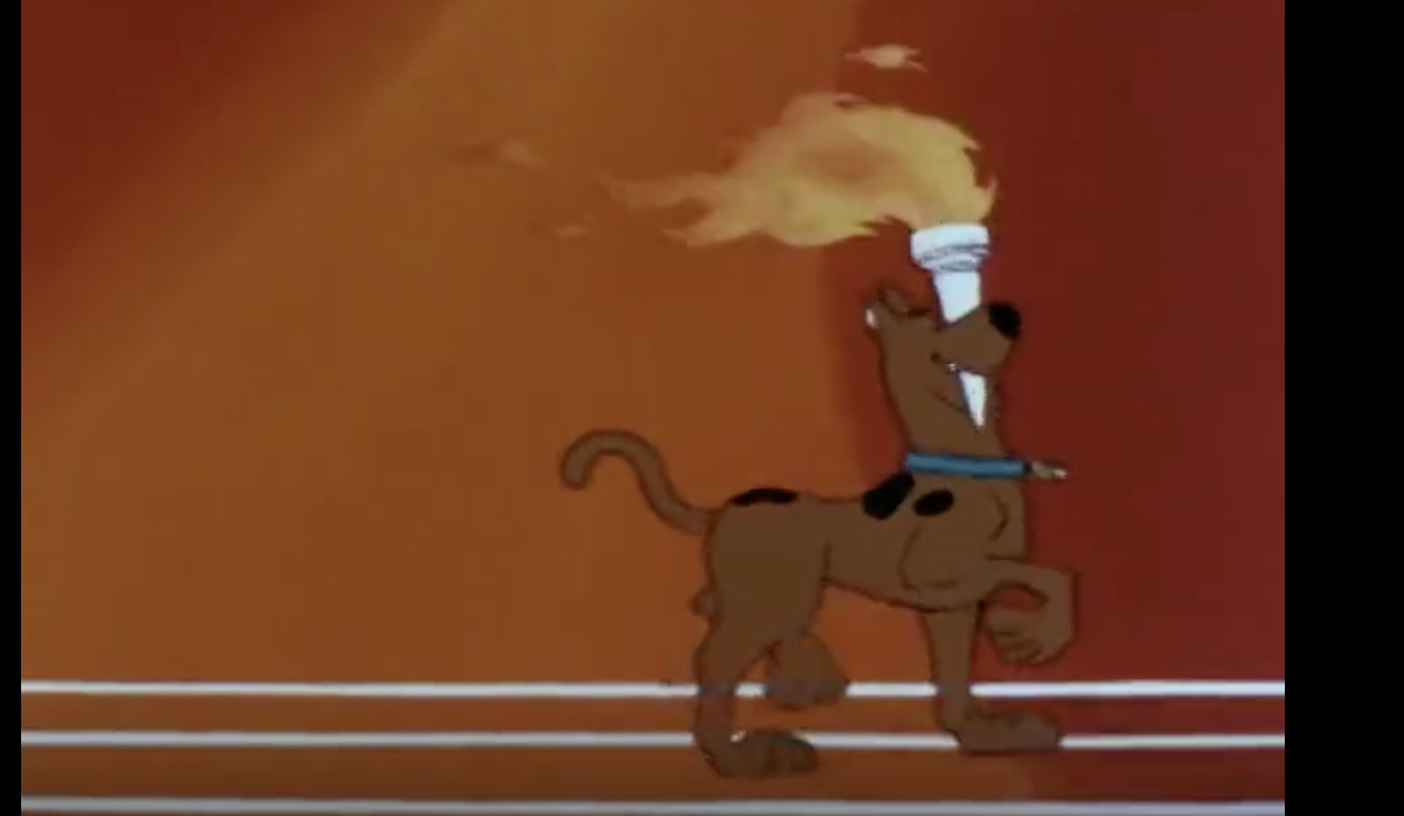 image from the 1977 cartoon show "Laff-a-Lympics." it shows animated Great Dance Scooby-Doo proudly carrying an Olympic torch in his mouth as he struts along.