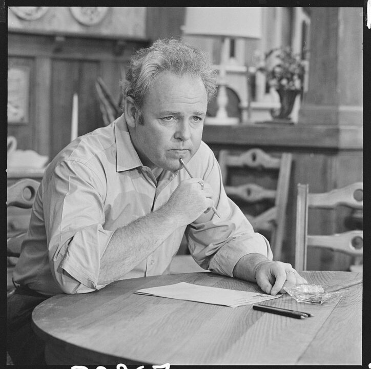 American actor Carroll O'Connor (1924 - 2001), as Archie Bunker, sits at a round table and thinks, a pencil to his chin, as he writes a letter in a scene from an episode of the television series 'All in the Family' entitled 'Writing the President,' Los Angeles, California, December 22, 1970. The episode was originally broadcast on January 19, 1971