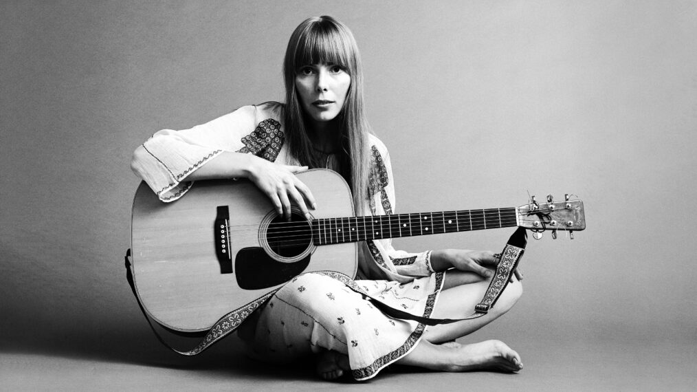 20th November 1968: Portrait of American musician Joni Mitchell seated on the floor with her acoustic guitar in her lap. This image was from a shoot for the fashion magazine Vogue. Mitchell wears a white cotton dress.