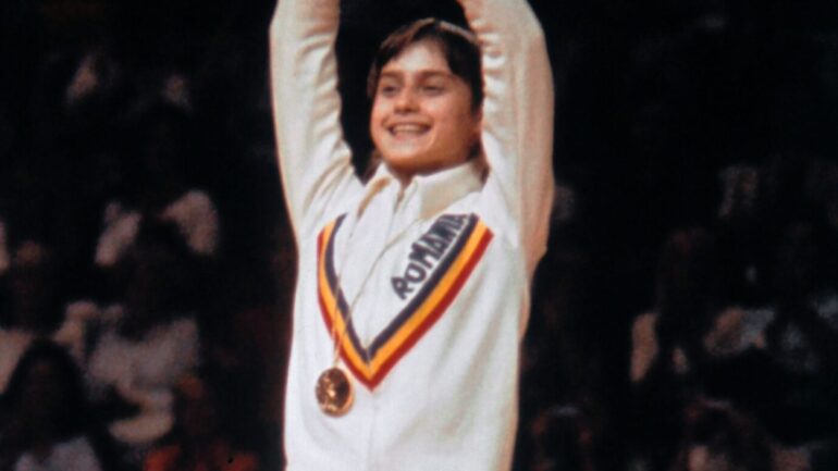 Romanian champion Nadia Comaneci, aged 14, wawes on the women' s Olympic uneven bars event podium of the Montreal 1976 Olympic Games on July 24, 1976 in Montreal. Legendary gymnast, during her career Nadia Comaneci captured four Olympic gold medals and was the first to score 10 in her discipline. At left, silver medalis Romanian Teodora Ungureano. / AFP / EPU / -