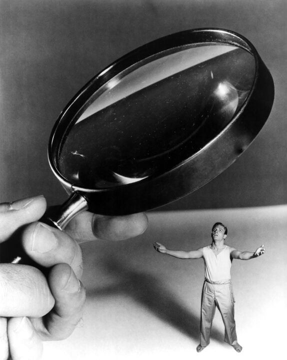 a scene of a tiny man being looked at with a magnifying glass in THE INCREDIBLE SHRINKING MAN