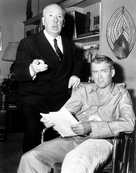 REAR WINDOW, from left: director Alfred Hitchcock, James Stewart on set, 1954