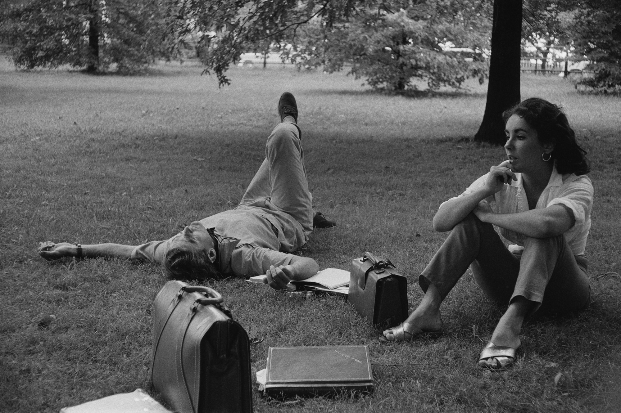 Actors Montgomery Clift and Elizabeth Taylor lounging on the grass during the filming of 'Raintree County' in Indiana, 1956.